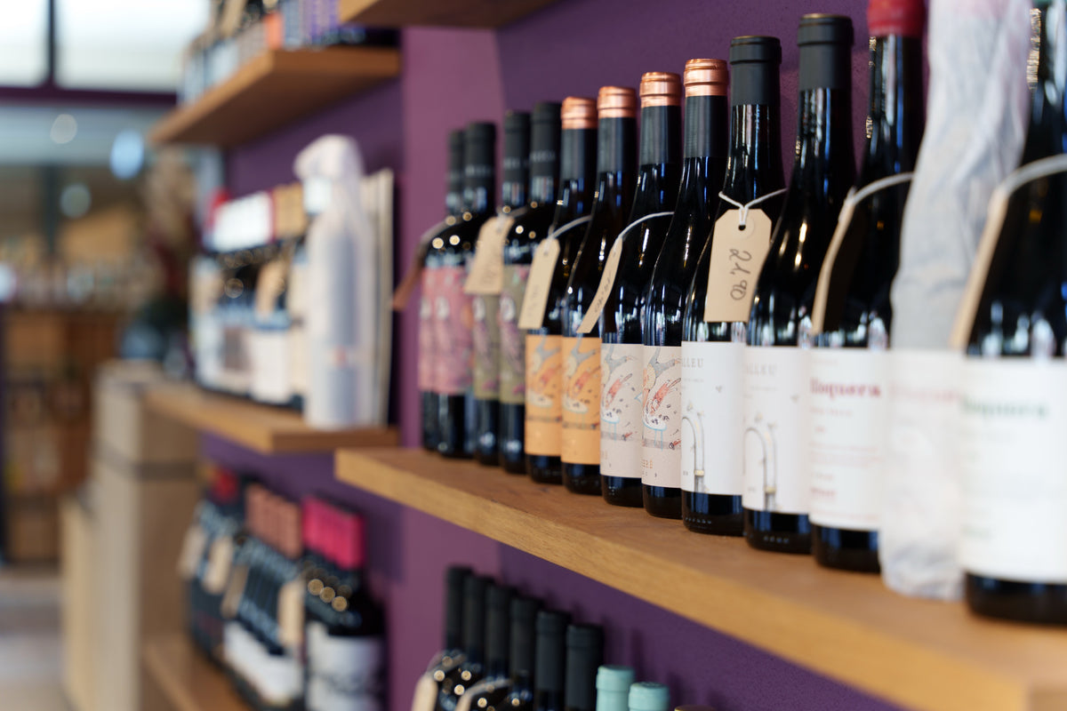 Weinflaschen vor der violetten Wand der Vinothek